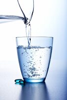 Wasser aus Krug in ein Glas gießen