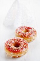 Two doughnuts with red glaze and sugar balls