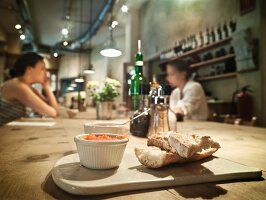 Weißbrot und Tomatenaufstrich in einem Lokal, Frauen im Hintergrund