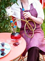 Person sitting on terrace with a hookah pipe
