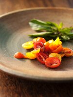 Sliced Red and Yellow Cherry Tomatoes with Fresh Basil in a Ceramic Plate