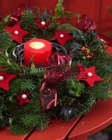 Adventskranz mit Kerze und roten Filzsternen auf einem Holztisch