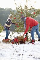 Paar schmückt einen Christbaum im Wald