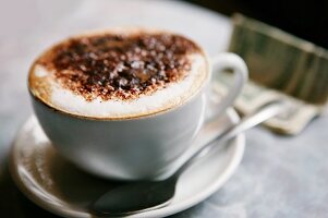 Eine Tasse Cappuccino, im Hintergrund mit Dollar-Scheine
