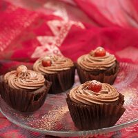 Chocolate cupcakes with glacé cherries on a glass plate