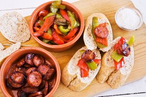 Peppers with chorizo and bread on a wooden board (Spain)