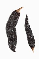 Two dried chillies against a white background