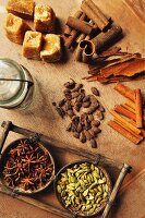 Assorted spices on a wooden table (cinnamon bark, cinnamon sticks, star anise, cardamom and palm sugar)