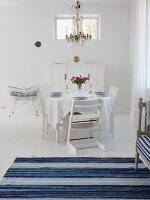 Esszimmer in schwedischem Stil in weiss & blau mit gedecktem Tisch & Kronleuchter