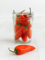 Whole orange chillies in front of and in a jar