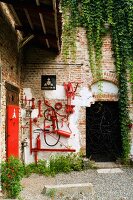 Hausecke einer ehemaligen Fabrik mit einer künstlerischen Installation aus rot lackierten Werkzeugen an Ziegelwand
