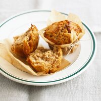 Apple and walnut muffins in baking parchment on a plate