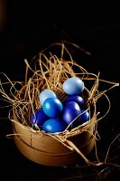 Blue Easter eggs in straw in a woodchip basket