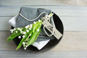 Lily of the valley and name tag on linen napkin in bowl