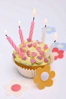 A cupcake decorated with sugar hearts and candles for Valentine's Day