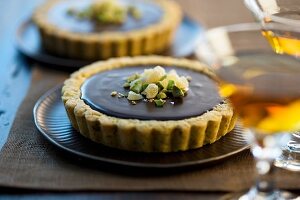 Ganache tart with a pistachio crust and a cocktail in the foreground