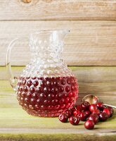 A jug of cherry juice with fresh cherries