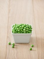 A bowl of fresh peas on a wooden table
