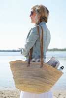 Blonde Frau mit Picknicktasche am Strand