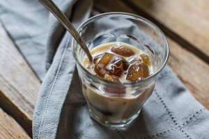 A glass of coffee with ice cubes