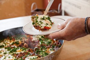 Shakshouka (Nordafrikanisches Pfannengericht mit Eiern) servieren