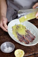 Sauce being poured over anchovies