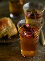 Spiced tea with star anise and rose petals and a baklava in the background
