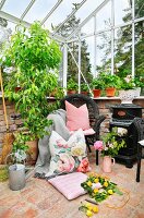 Wicker chair, scatter cushions and retro wood-burning stove in conservatory