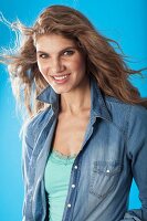 A young brunette woman wearing a denim shirt and a turquoise top