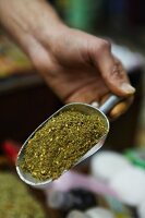 A hand holding a scoop of spice mix at a market