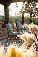 Stühle auf überdachter Terrasse mit dekorativer Grasbepflanzung