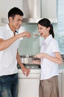 Man feeding woman with a spoon in the kitchen