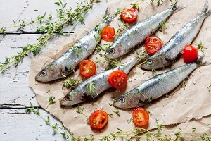 Fresh, raw sardines seasoned with salt and thyme with halved cherry tomatoes