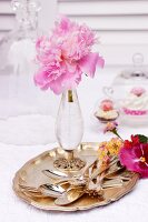 Peonies in crystal vase and cutlery on silver tray