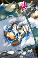 A partitioned bread basket for baguette slices and a serving platter on a breakfast table in a garden