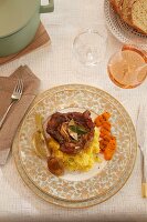 And elegant place setting with veal knuckle in wine and lemons on polenta, main course