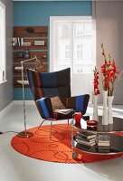 A classic wing chair and a mobile side table on a round, red felt rug in a modern setting