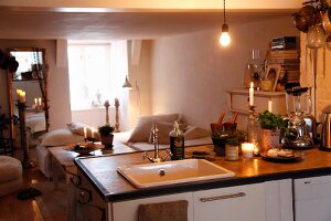 Blick über Küchentheke mit Kochutensilien in schlichten Wohnbereich, im Hintergrund gemütliche Polsterbänke