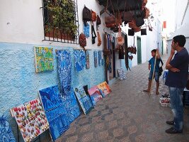Paintings and artistic handicrafts on a wall in the Medina of Asilah, Morocco