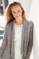 Junge, blonde Frau in weisser Spitzenbluse und grauer Strickjacke