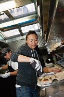 Köchin bereitet Tacos zu in einem Food Truck (USA)