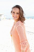 Junge Frau in apricotfarbenem Sommerpulli am Strand