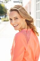 A young blonde woman wearing a salmon pink blouse