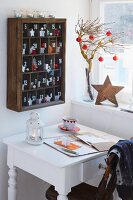 A wooden cabinet hanging on the wall as an advent calendar with a white desk in front of it
