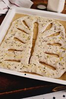 Unbaked fougasse with bacon and walnuts on a baking tray