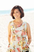 Brunette woman wearing floral summer dress on beach