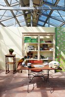 Glass and metal ceiling, partition with open-fronted shelves, terracotta-tiled floor and various ornaments