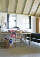 Sewing table; sewing machine on simple wooden table and basket of fabric remnants in rustic interior