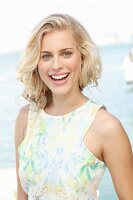 A blonde woman by the sea wearing a shirt with a pastel coloured pattern