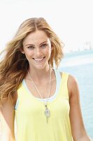A blonde woman wearing a light yellow top in the fashionable necklace